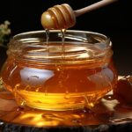 Barattolo di miele con un cucchiaino, su un tavolo, simbolo dei benefici del consumo quotidiano di miele.