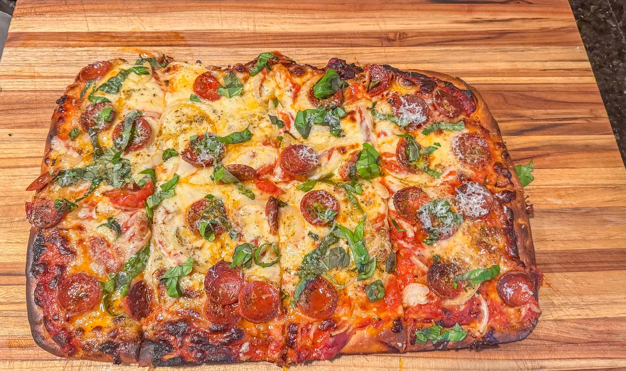 Pizza in teglia appena sfornata, con bordo dorato e soffice, su un tavolo di legno.