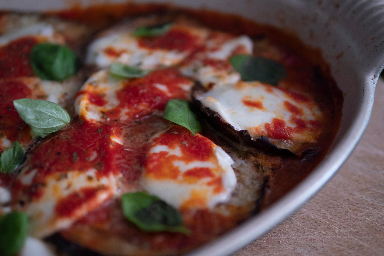 Parmigiana di melanzane perfettamente dorata e non unta, servita su un piatto bianco.