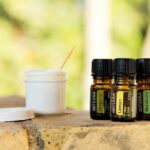 Flacone di repellente per zanzare fai-da-te con ingredienti naturali su un tavolo di legno.