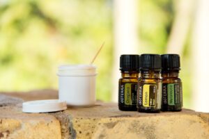 Flacone di repellente per zanzare fai-da-te con ingredienti naturali su un tavolo di legno.