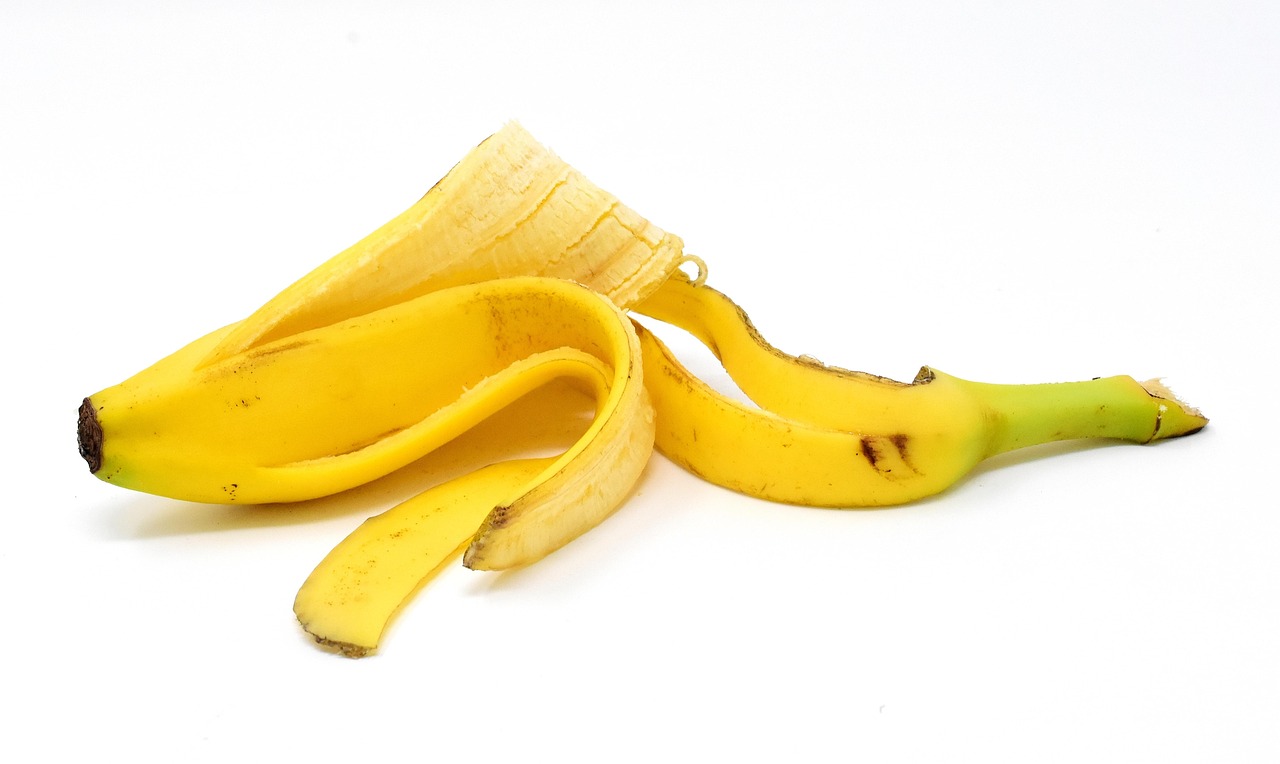 Buccia di banana accanto a piante verdi in vaso, simbolo di fertilizzante naturale per la crescita.